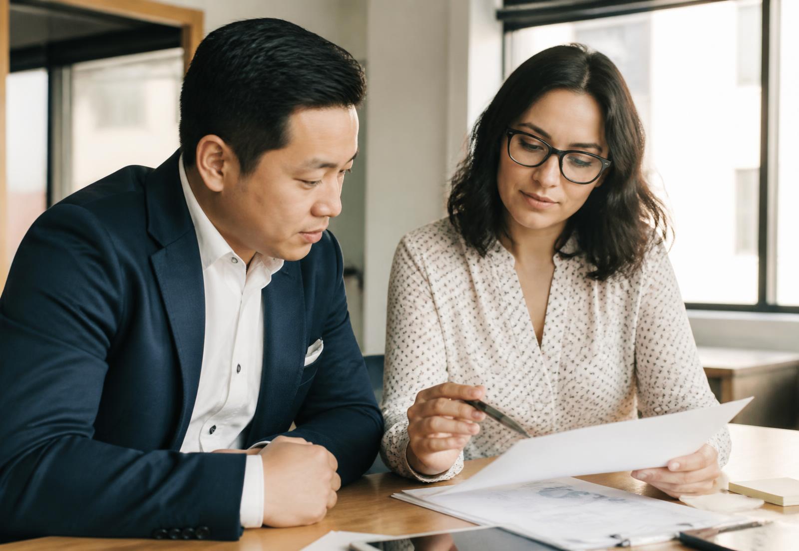 Two advisors reviewing documents together in a bright office